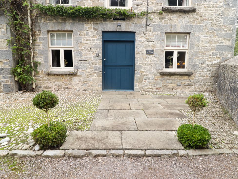A front entrance with a blue door and stone pathway at The Stables at Gileston Manor St Athan