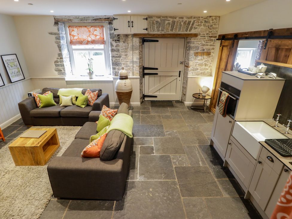 A living room with sofas and a kitchen area at The Stables at Gileston Manor St Athan