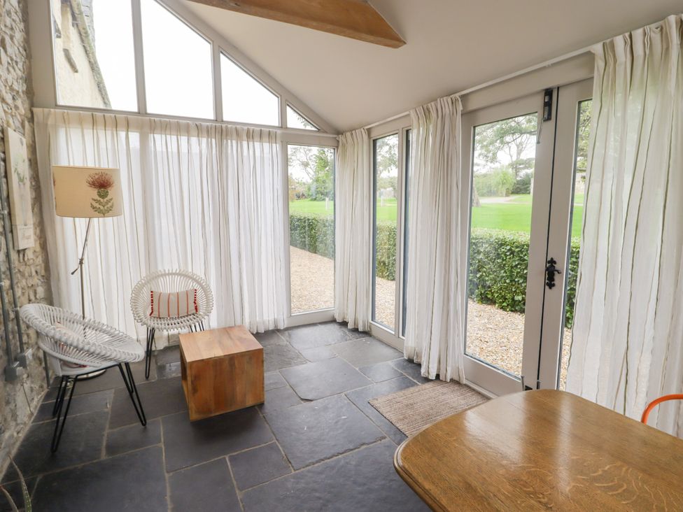 A conservatory with windows and a small table at The Stables at Gileston Manor, St Athan