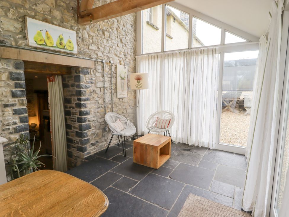 A sunroom with stone walls and seating at The Stables at Gileston Manor St Athan