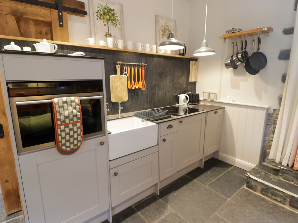 A kitchen with cabinets, sink, and utensils at The Stables at Gileston Manor St Athan