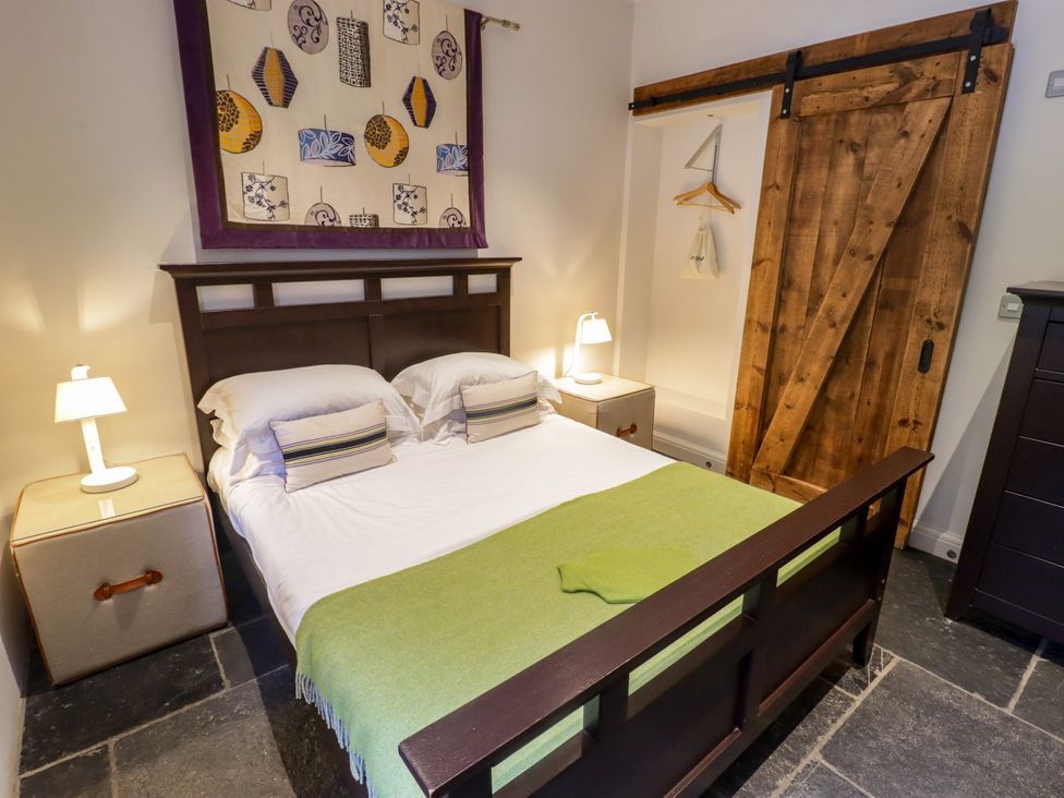 A bedroom with a bed, bedside table and lamp at The Stables at Gileston Manor St Athan