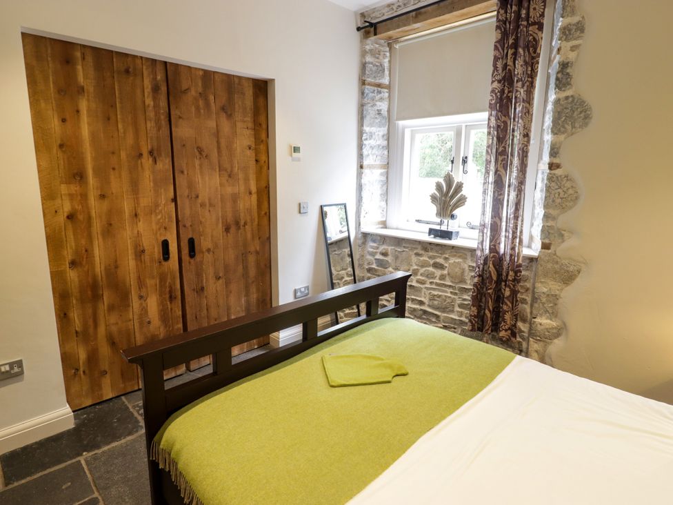 A bedroom with a bed and wooden wardrobe at The Stables at Gileston Manor in St Athan