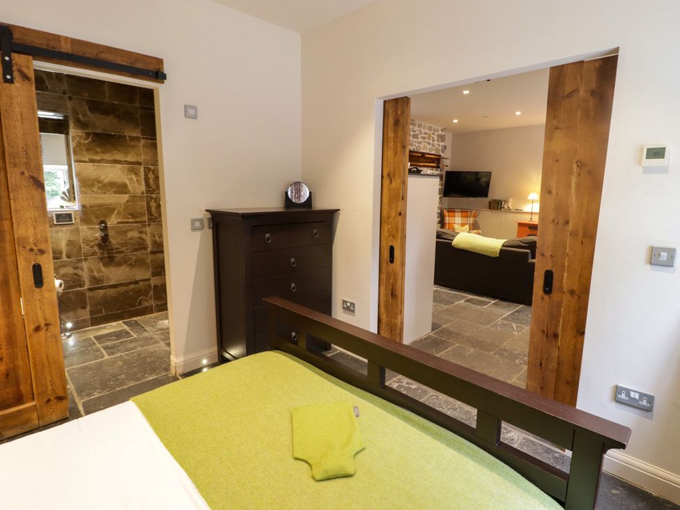 A bedroom with a dresser and sliding door leading to a living area at The Stables at Gileston Manor St Athan