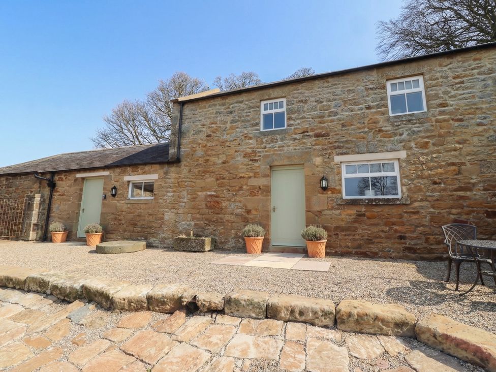 An outdoor view of a stone building with a green door at Cragg Lodge West Woodburn