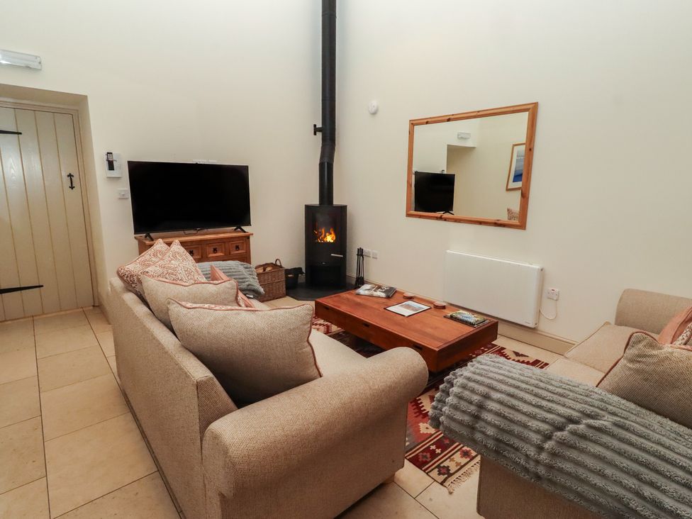 A living room with a television and wood stove at Cragg Lodge in West Woodburn