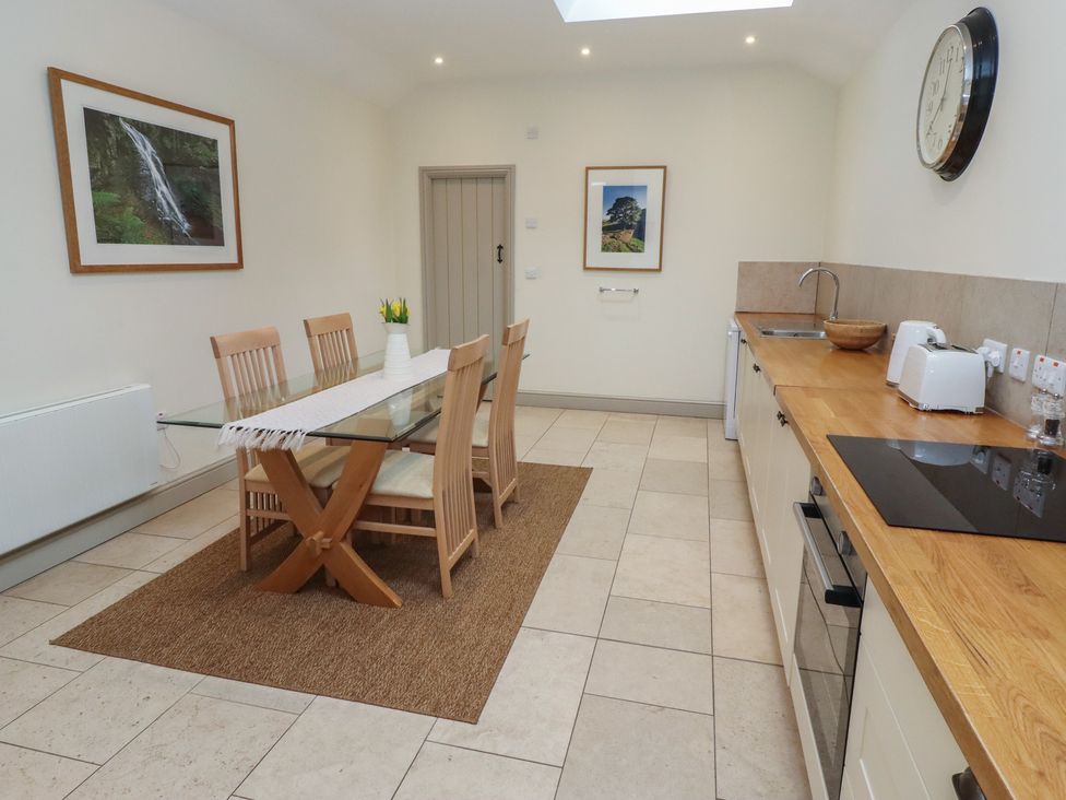 A kitchen with a dining table and chairs at Cragg Lodge in West Woodburn