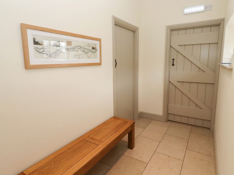 A hallway with a bench and framed artwork at Cragg Lodge in West Woodburn