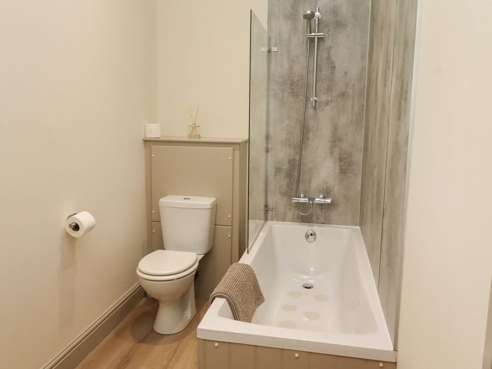 A bathroom with a toilet and bathtub at Cragg Lodge in West Woodburn