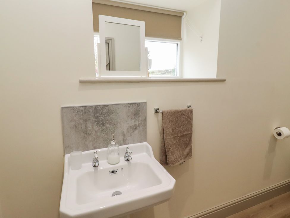 A bathroom with a sink and mirror at Cragg Lodge in West Woodburn