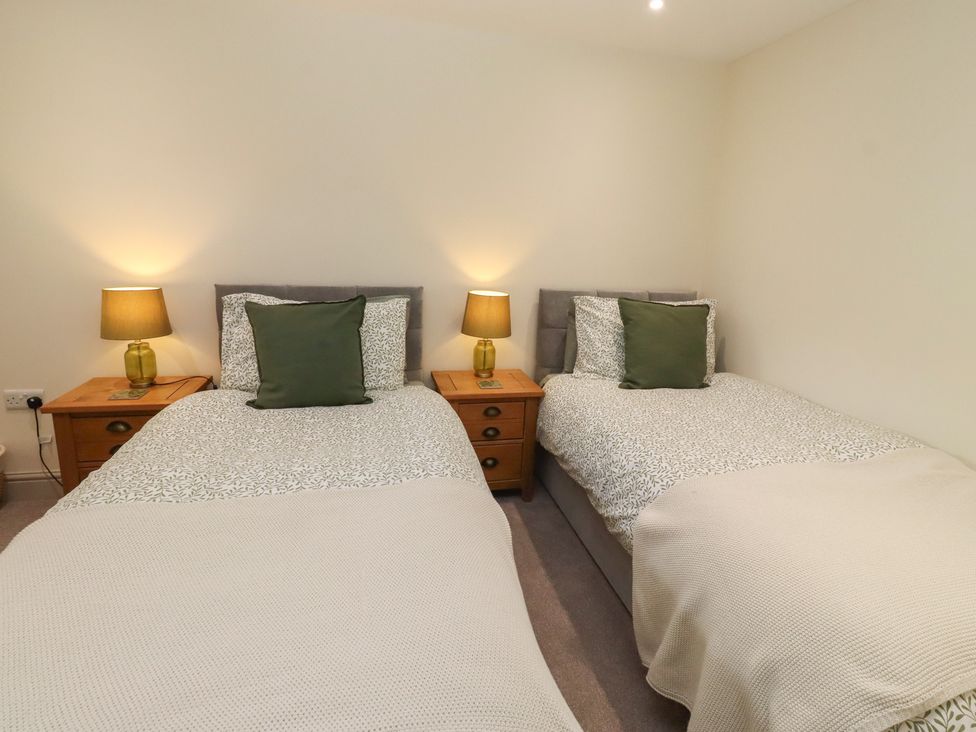 A bedroom with two beds and nightstands at Cragg Lodge West Woodburn