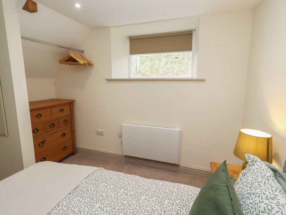 A bedroom with a bed and dresser at Cragg Lodge West Woodburn