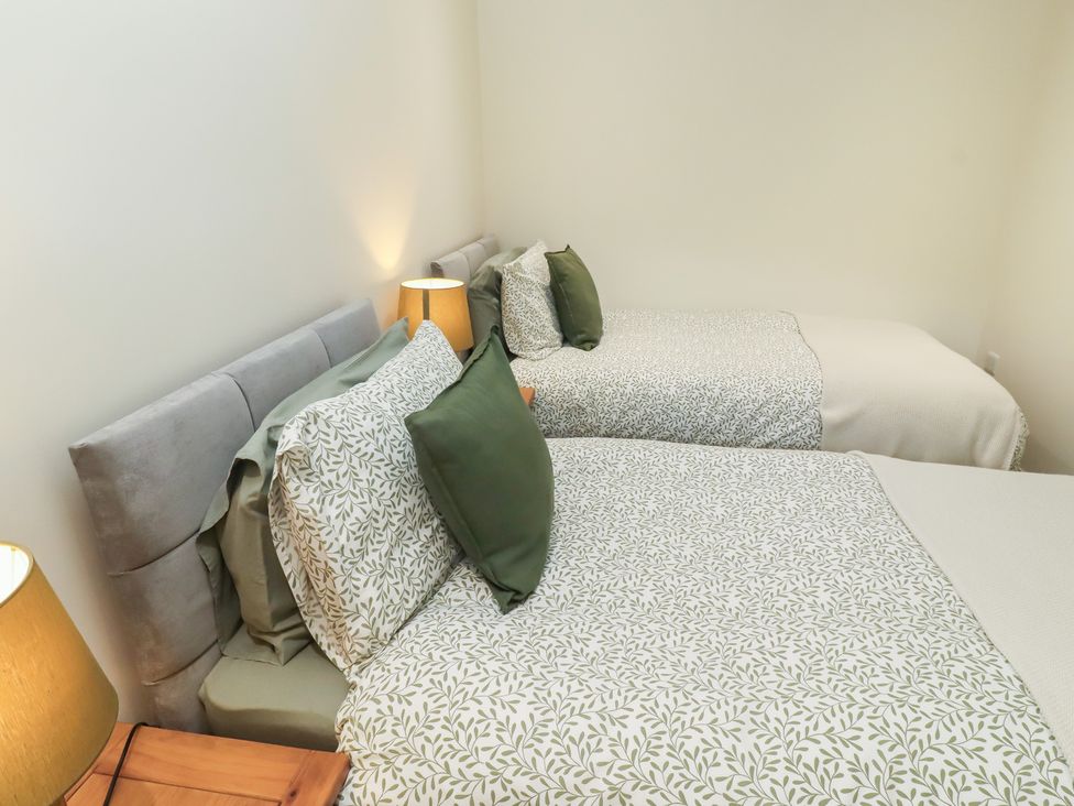 A bedroom with two beds and bedside lamps at Cragg Lodge in West Woodburn