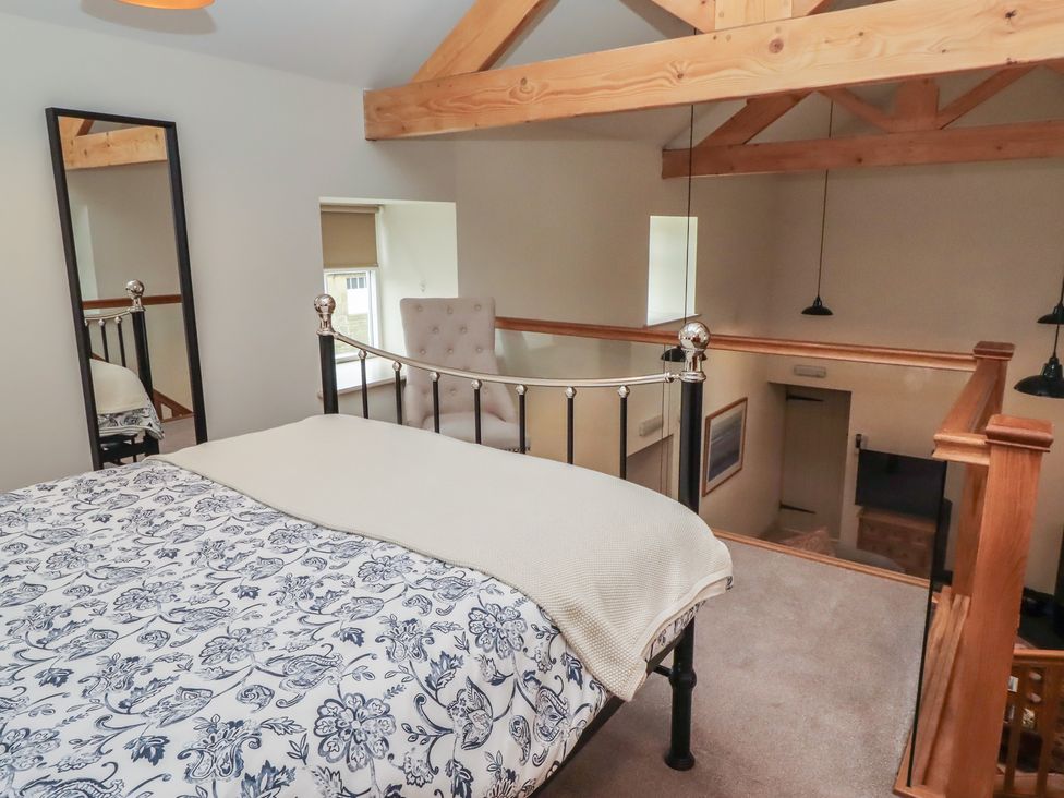 A loft bedroom with a bed and a chair at Cragg Lodge in West Woodburn
