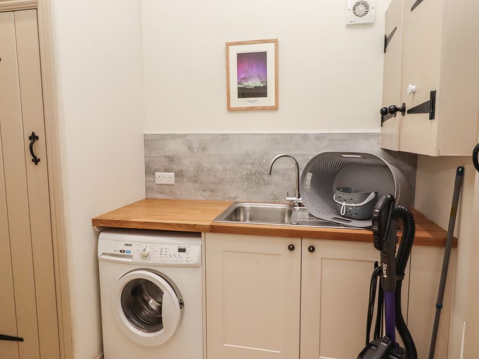 A utility room with washing machine and sink at Cragg Lodge in West Woodburn