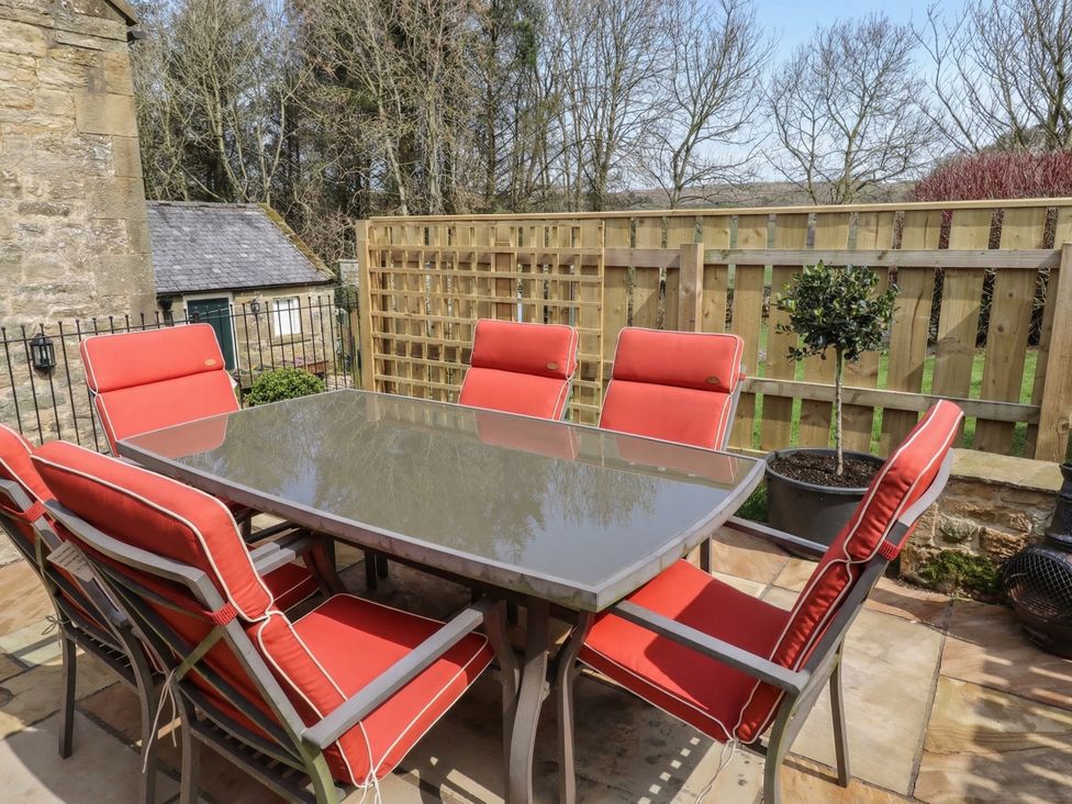 An outdoor seating area with a table and chairs at Cragg Lodge in West Woodburn