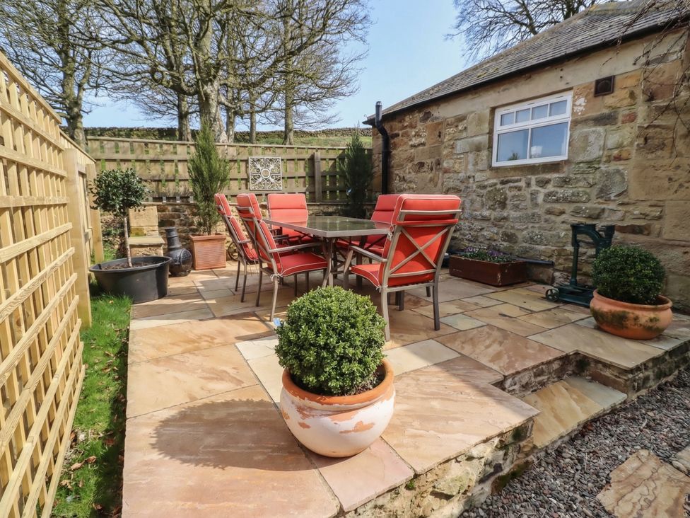 A garden with a table and chairs at Cragg Lodge in West Woodburn