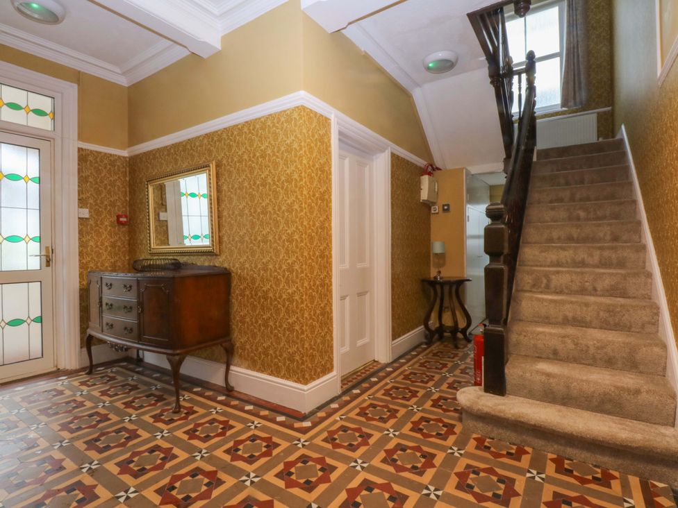 A hallway with a staircase and a chest of drawers at Southbourne Manor in Llandudno