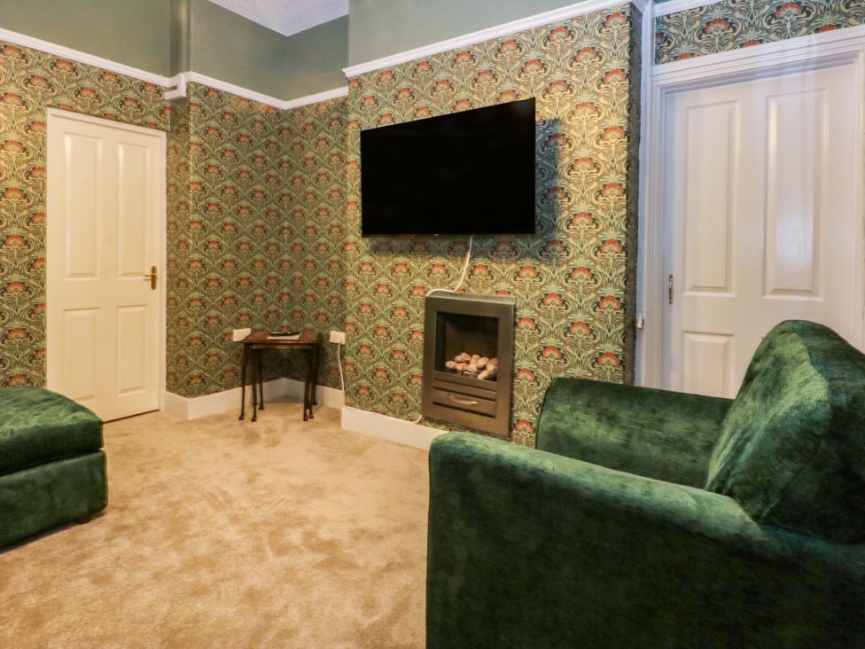 A living room with a television and sofa at Southbourne Manor in Llandudno