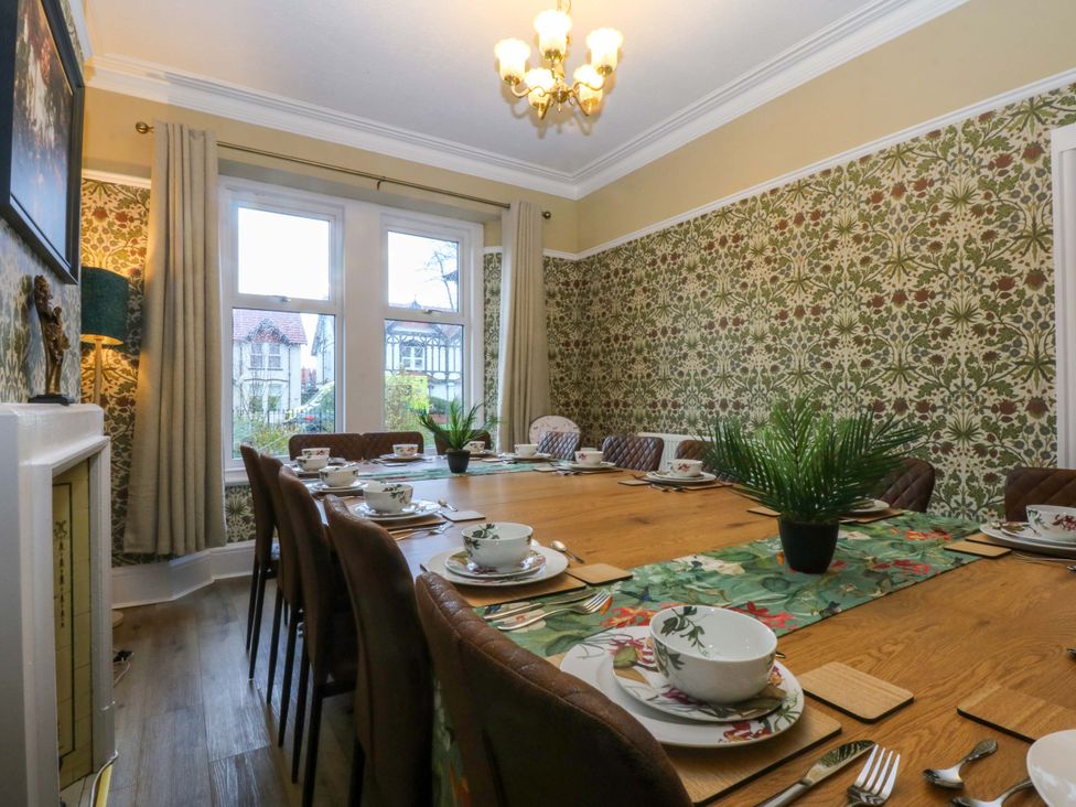 A dining room with a large table set with dishes at Southbourne Manor in Llandudno