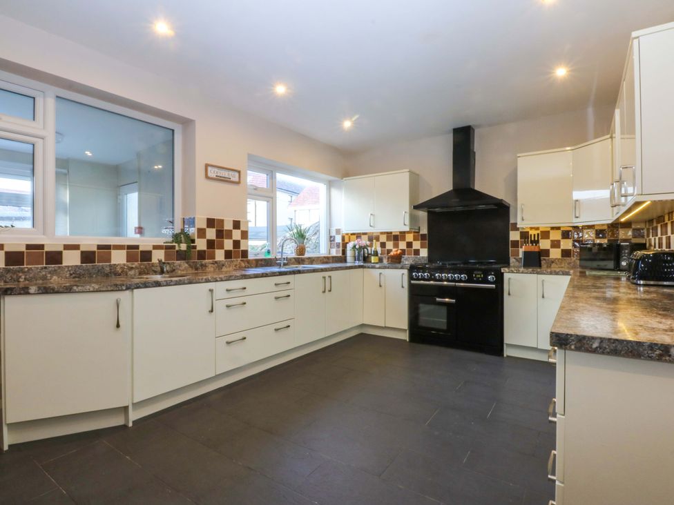 A kitchen with cabinets, counter, oven, and windows at Southbourne Manor in Llandudno