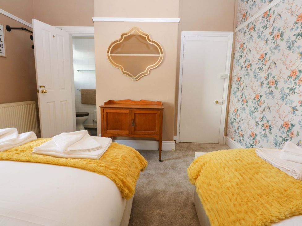 A bedroom with two beds and a wooden cabinet at Southbourne Manor in Llandudno