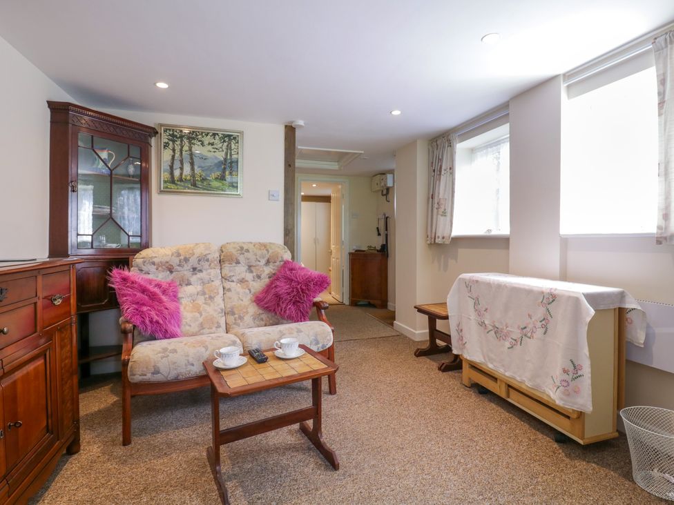 A sitting room with a floral sofa and wooden furniture at The Cottage in Sudbury