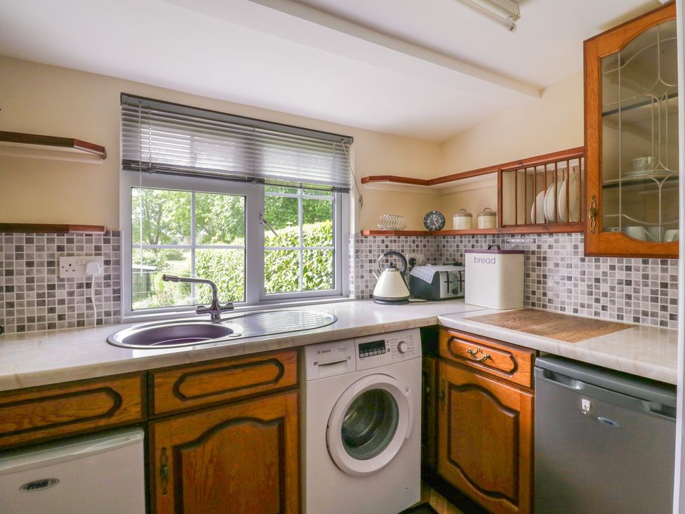 A kitchen with a sink washing machine kettle toaster and bread bin at The Cottage in Sudbury