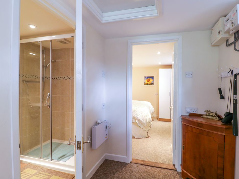 Hallway with doors to a tiled shower room and a bedroom with a bed and a wardrobe at The Cottage in Sudbury