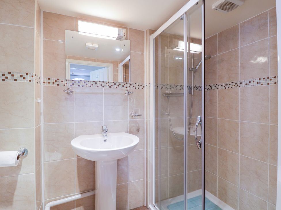 A bathroom with a pedestal sink a glass shower enclosure and a wall mirror at The Cottage in Sudbury