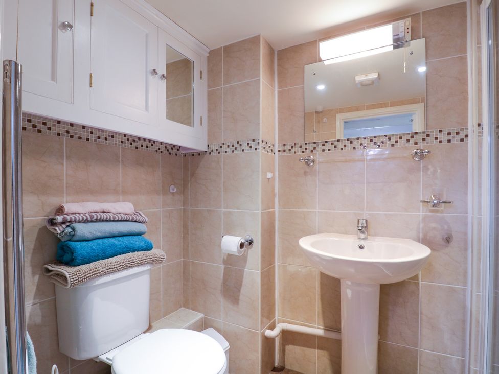 A bathroom with a toilet and a pedestal sink under a wall mirror at The Cottage in Sudbury