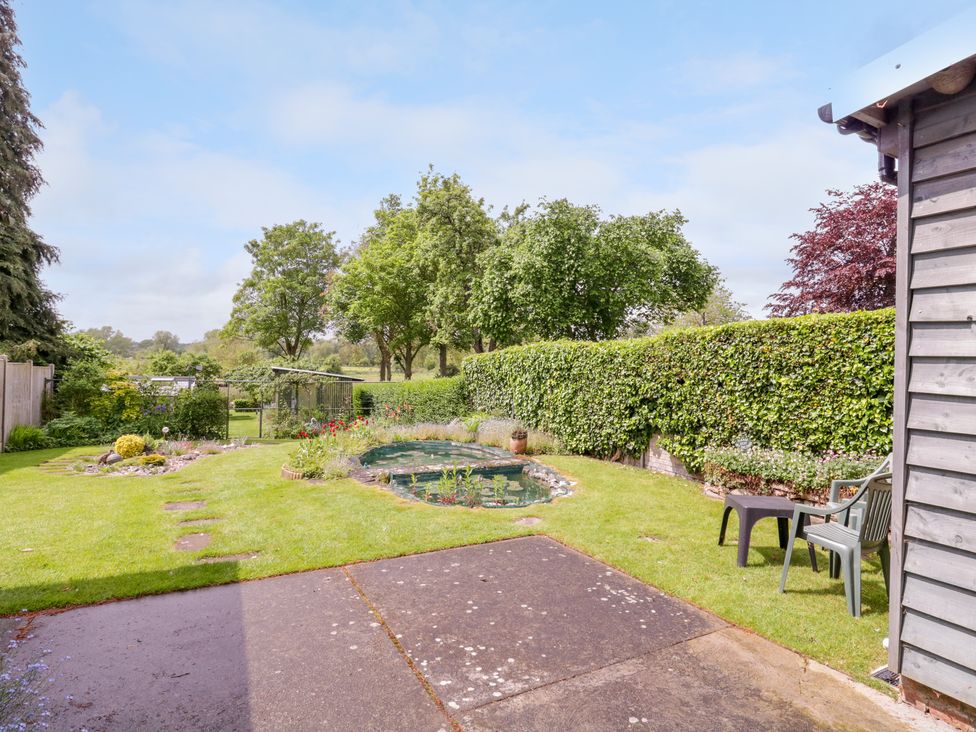 A garden with a small pond surrounded by grass and trees at The Cottage in Sudbury