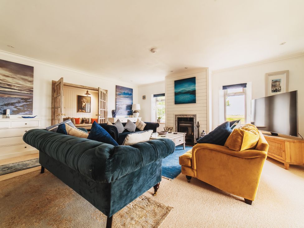 A living room with a blue sofa and yellow armchair at Glanllyn Bach Llanfaelog