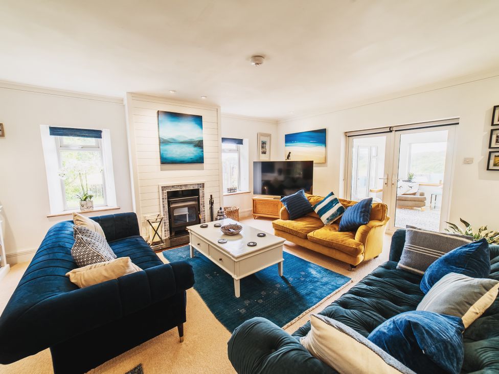 A living room with sofas and a television at Glanllyn Bach in Llanfaelog