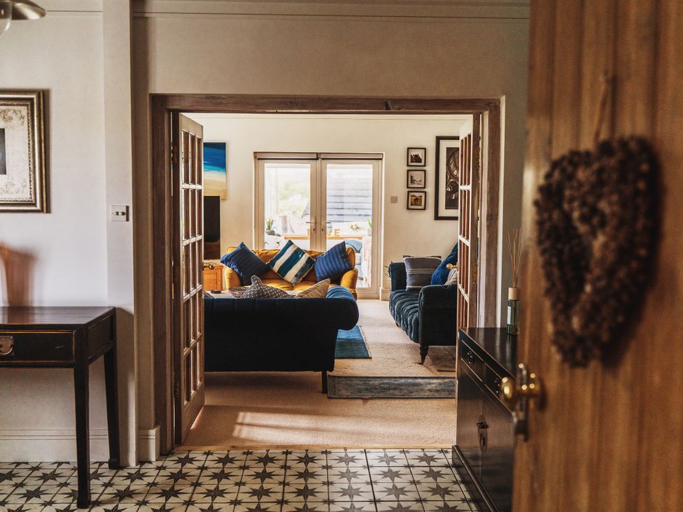 A view into a living room with a sofa and table at Glanllyn Bach, Llanfaelog