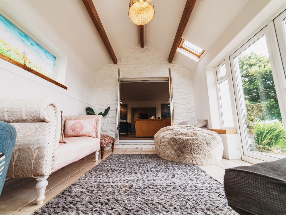 A living room with a sofa, rug, and bean bag at Glanllyn Bach in Llanfaelog