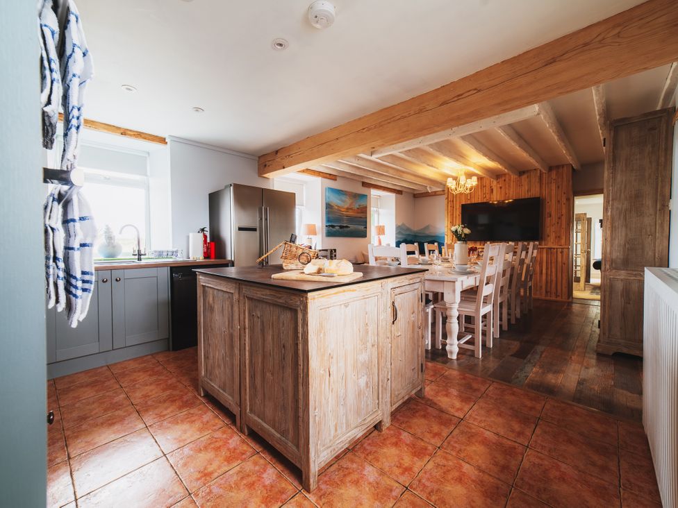 A kitchen with an island and dining area at Glanllyn Bach in Llanfaelog