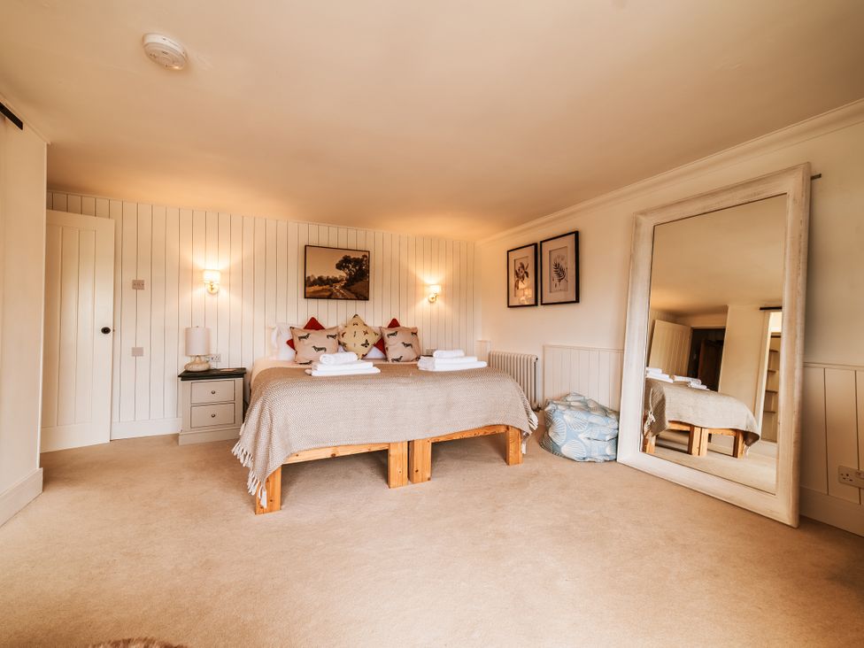 A bedroom with a bed and mirror at Glanllyn Bach in Llanfaelog