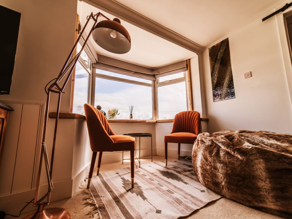 A living room with two armchairs and a table at Glanllyn Bach in Llanfaelog