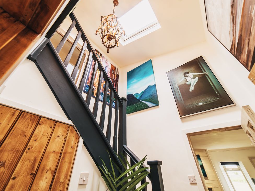 A staircase with a chandelier and artwork at Glanllyn Bach in Llanfaelog
