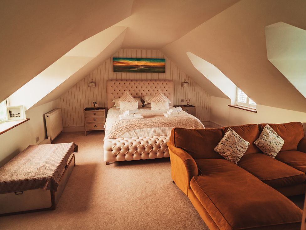 A bedroom with a bed and sofa at Glanllyn Bach in Llanfaelog