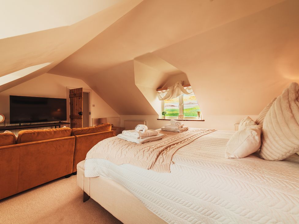 A bedroom with a bed and television at Glanllyn Bach Llanfaelog