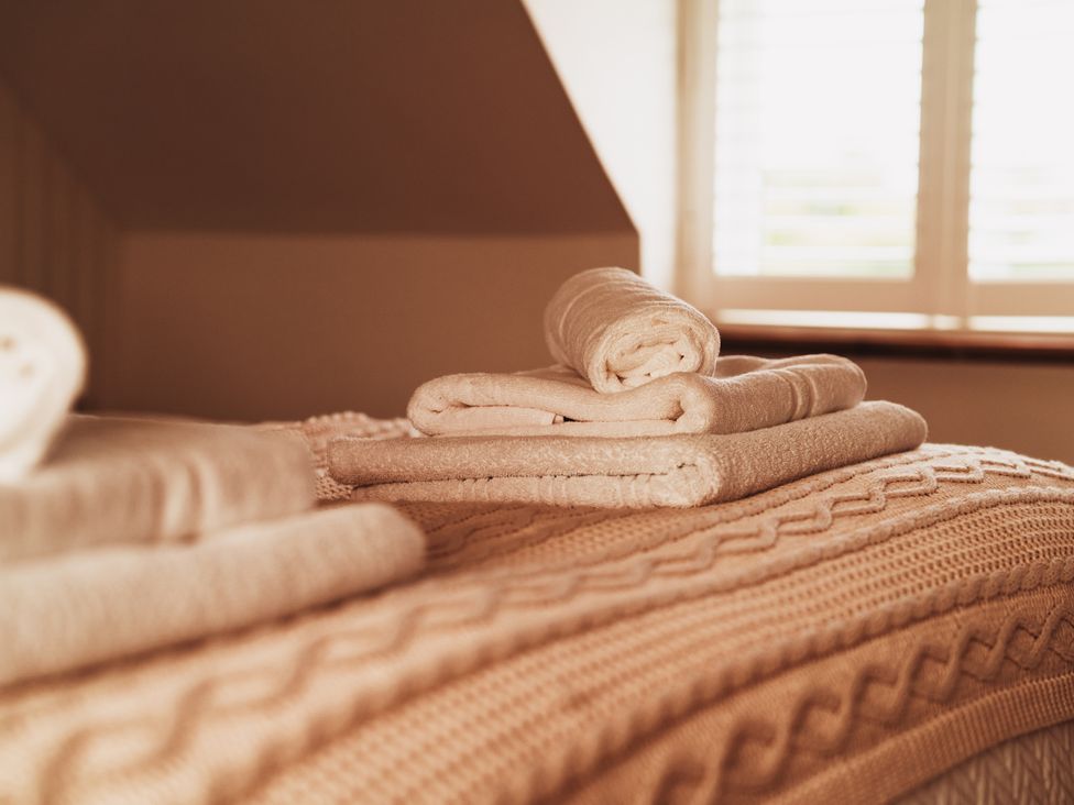 Towels and a blanket on a bed at Glanllyn Bach in Llanfaelog