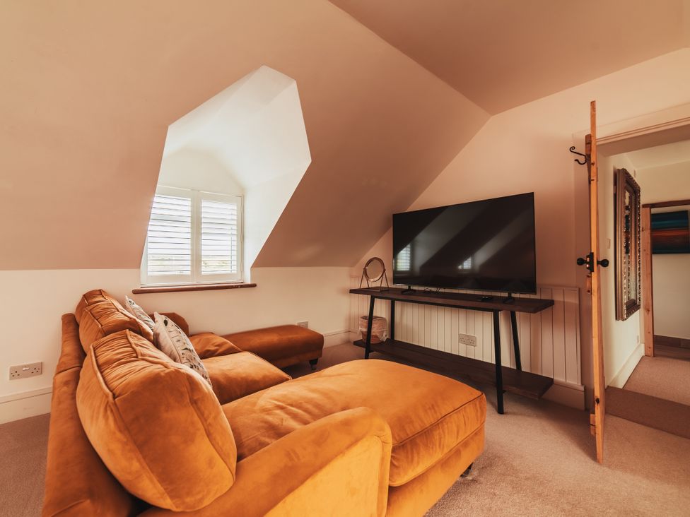 A living room with a sofa and television at Glanllyn Bach in Llanfaelog