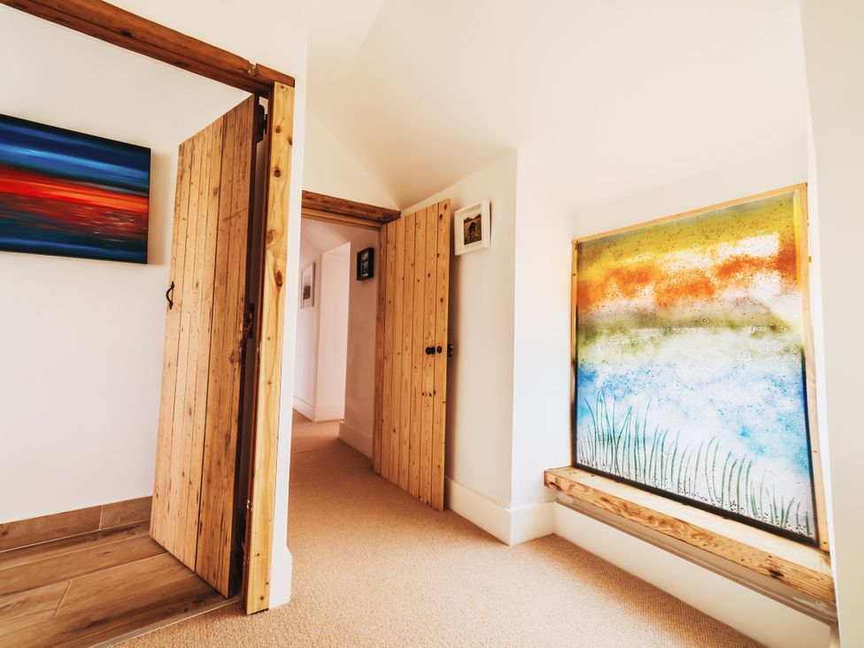A hallway with wooden doors and a window featuring artwork at Glanllyn Bach in Llanfaelog