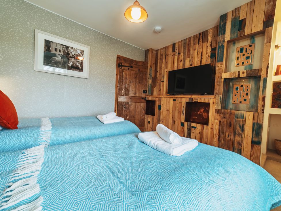 A bedroom with two beds and a television at Glanllyn Bach in Llanfaelog