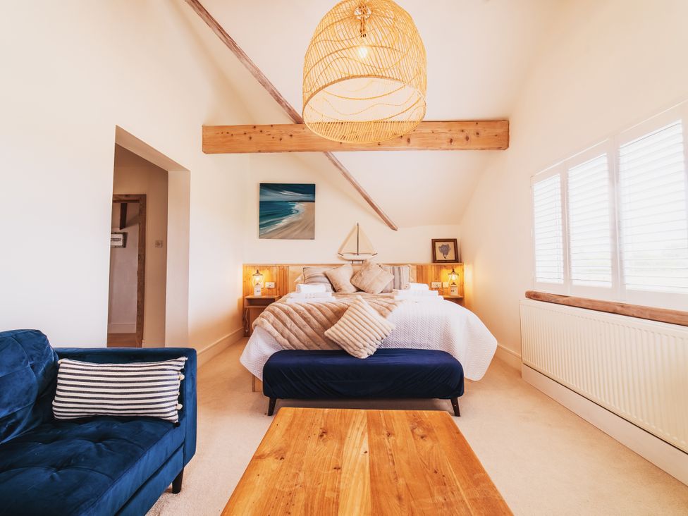 A bedroom with a bed and sofa at Glanllyn Bach Llanfaelog