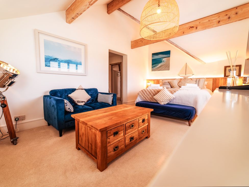 A bedroom with a blue sofa and wooden coffee table at Glanllyn Bach in Llanfaelog