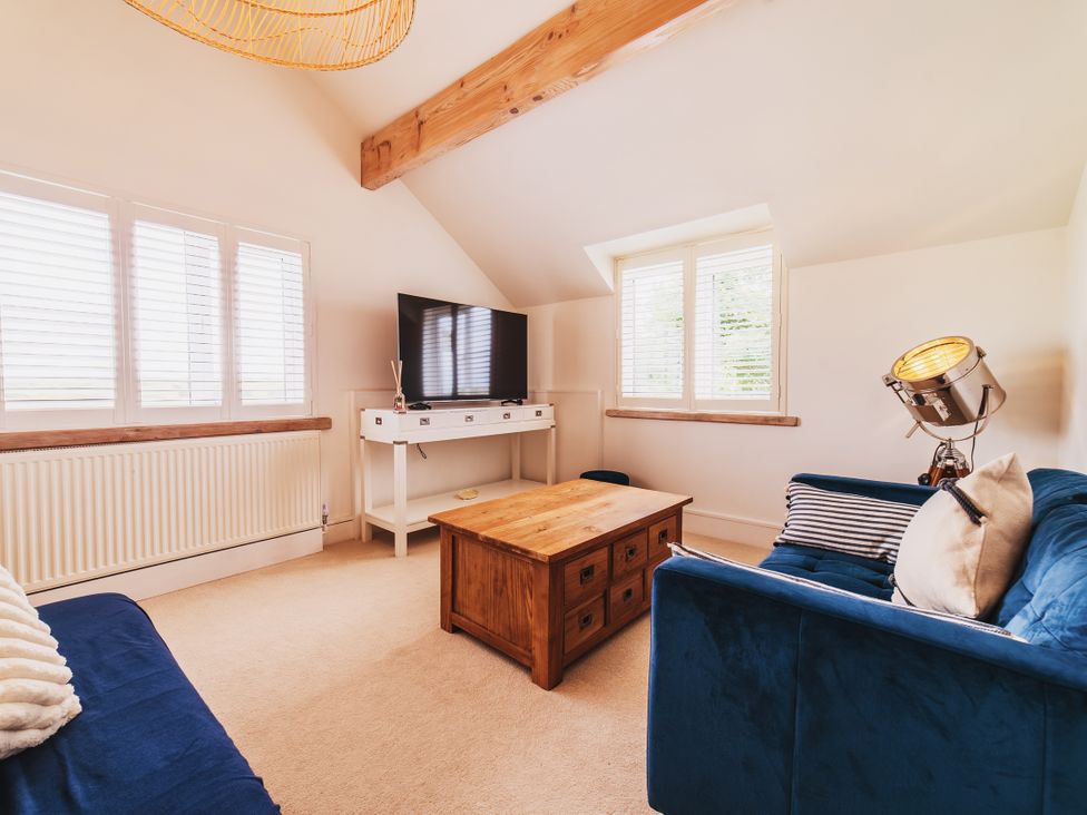 A living room with a coffee table and television at Glanllyn Bach in Llanfaelog