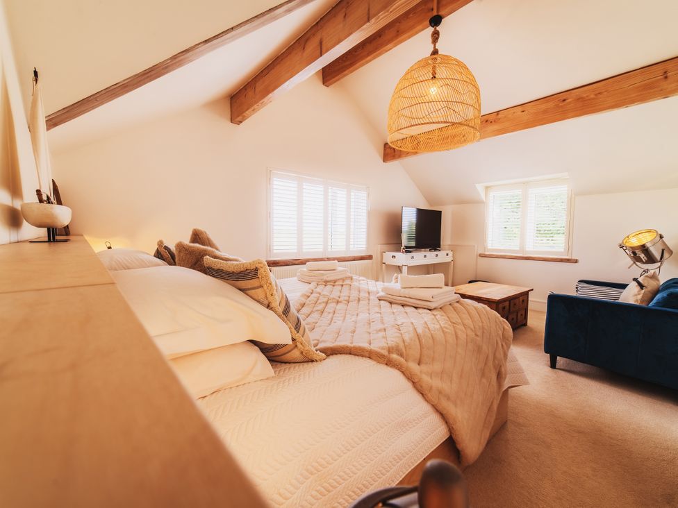 A bedroom with a bed, sofa and television at Glanllyn Bach in Llanfaelog